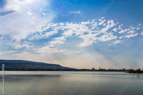 Lake with mirror-like water and sunlight passing through the clouds