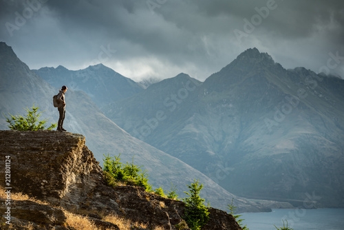 Young male photographer looking at mountain scenery during golden hour sunset in Queenstown, South Island, New Zealand. Travel and photography concept © zephyr_p