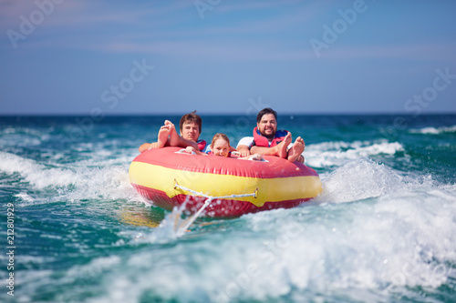 excited friends, family having fun, riding on water tube during summer vacation © Olesia Bilkei