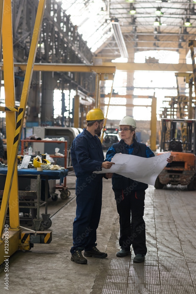 Technician discussing blueprint with his colleague Technician discussing blueprint with his colleague