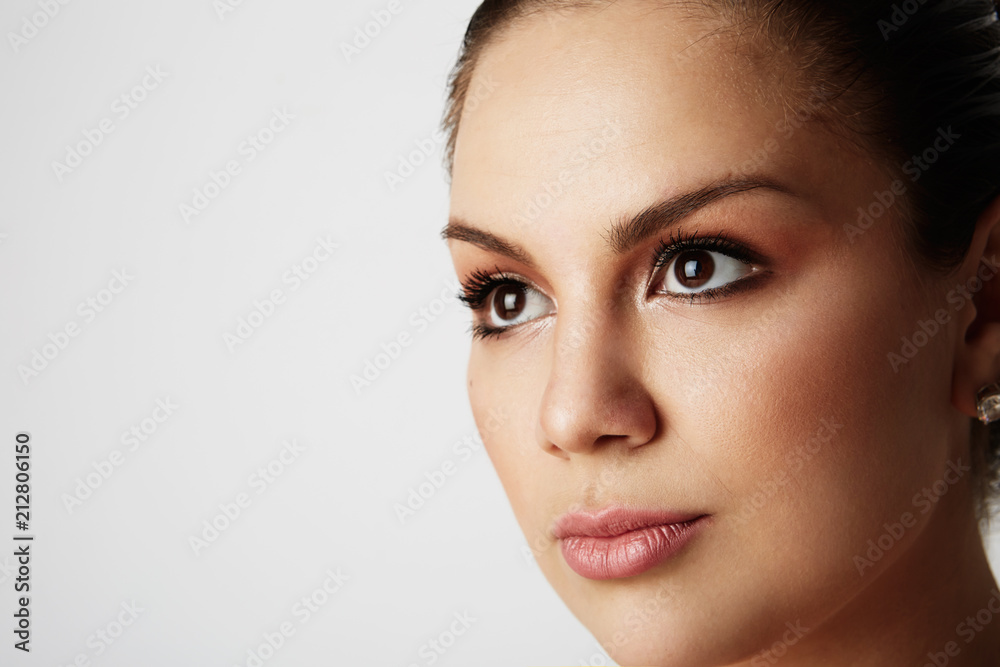 Portrait of handsome woman with big brown eyes and dark eyebrows looking away over empty studio background.Model with light nude make-up.Copy paste space,close up.Healthcare skin concept Portrait of handsome woman with big brown eyes and dark eyebrows looking away over empty studio background.Model with light nude make-up.Copy paste space,close up.Healthcare skin concept