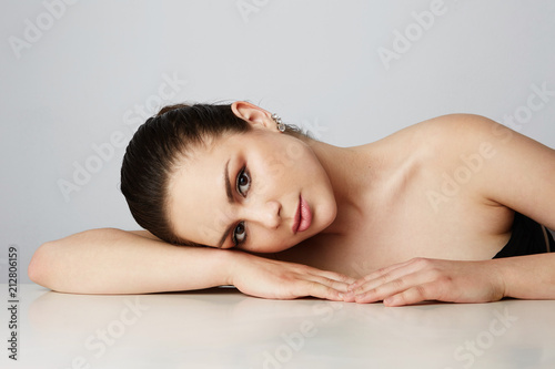 Beautiful women with big brown eyes and dark eyebrows relaxing over empty gray studio background.Model with light nude make-up.Copy paste space,close up.Healthcare skin concept
