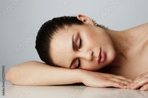 Beautiful women with dark eyebrows sleeping with over empty gray studio background.Model with light nude make-up.Copy paste text space,close up.Healthcare skin makeup concept