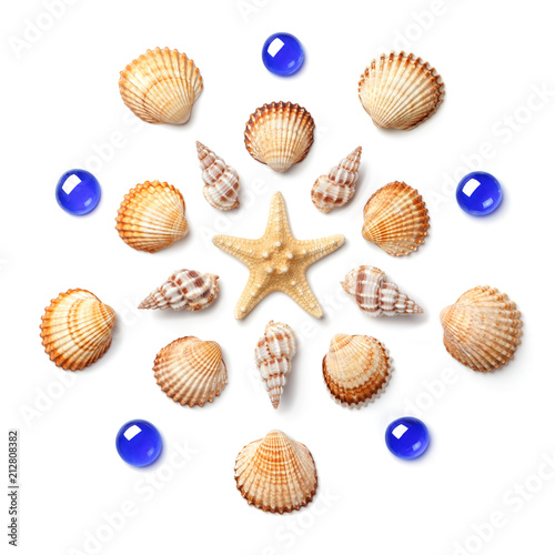 Pattern in the form of a circle made of shells, starfish and blue glass beads isolated on white background