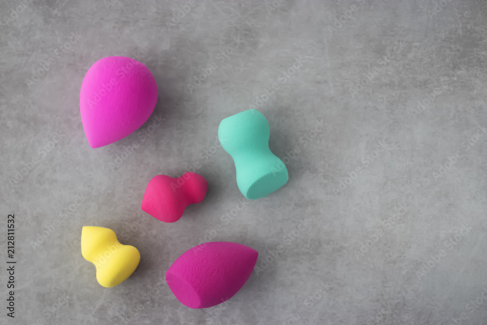 Fototapeta premium Multicolored cosmetic sponges on a gray concrete background.