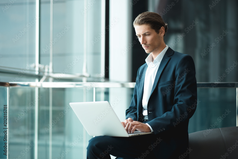 Young handsome man working in the office of mobile network company, adapting tariff plans to users need. Consultant providing service online with notebook. Business running through mobile systems. Young handsome man working in the office of mobile network company, adapting tariff plans to users need. Consultant providing service online with notebook. Business running through mobile systems.