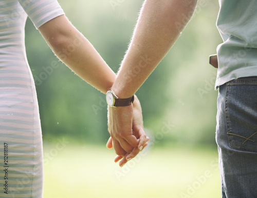two lovers gently holding each other's hands and walking in the park