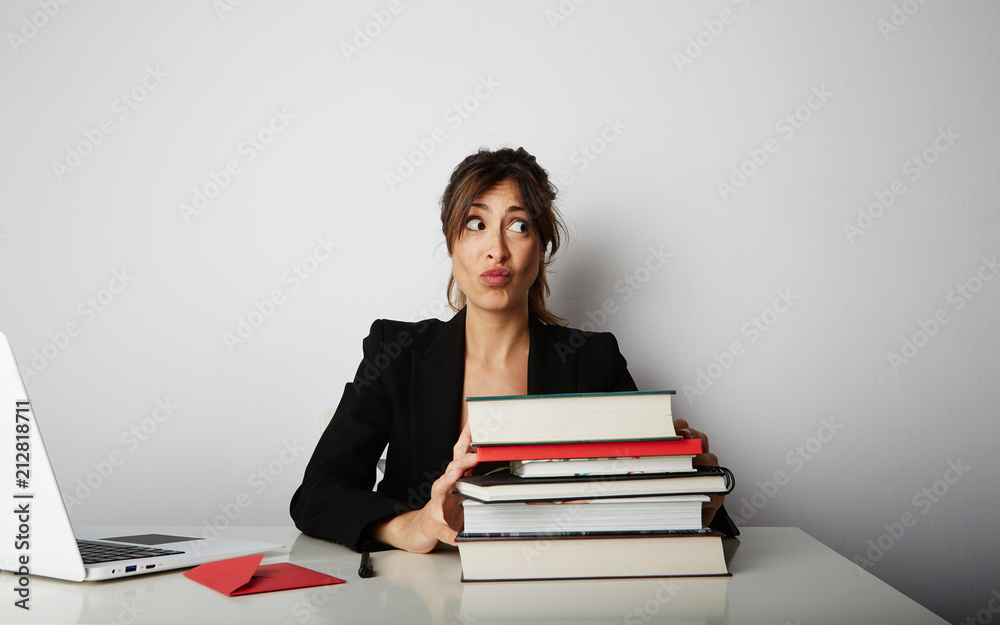 Young overwhelmed woman working hard. Young woman student shock of many books.Female model front of huge pile of books Young overwhelmed woman working hard. Young woman student shock of many books.Female model front of huge pile of books