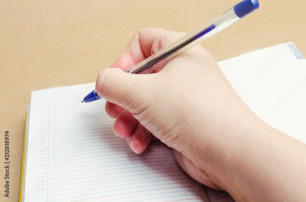a female hand writes in a notebook and makes notes, plans for the day, shopping list, close-up, businessman makes notes on the calendar, concept school and education a female hand writes in a notebook and makes notes, plans for the day, shopping list, close-up, businessman makes notes on the calendar, concept school and education