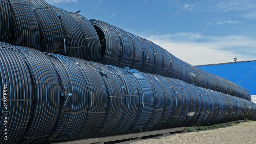 Warehouse of finished plastic pipes industrial outdoors storage site. Manufacture of plastic water pipes factory. Process of making plastic tubes on the machine tool with the use of water and air