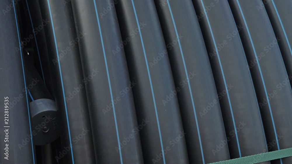 Fototapeta premium Warehouse of finished plastic pipes industrial outdoors storage site. Manufacture of plastic water pipes factory. Process of making plastic tubes on the machine tool with the use of water and air