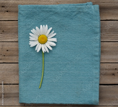 Daisy on blue napkin and wood background