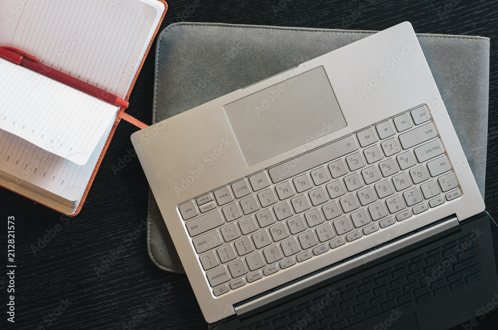 Opened laptop and notebook, top view. Computer on the desk with case, workspace Opened laptop and notebook, top view. Computer on the desk with case, workspace