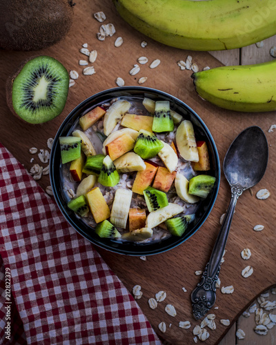Breakfast with oatmeal porridge with fruits. Oatmeal with kiwi, peach and banana. Healthy breakfast concept. Top view