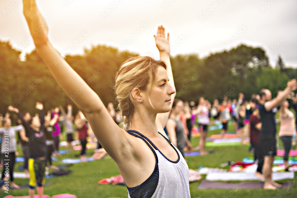 big group of adults attending a yoga class outside in park big group of adults attending a yoga class outside in park