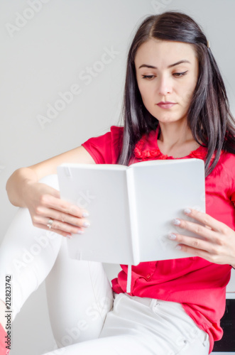 girl reads a book of white color, sits on a table
