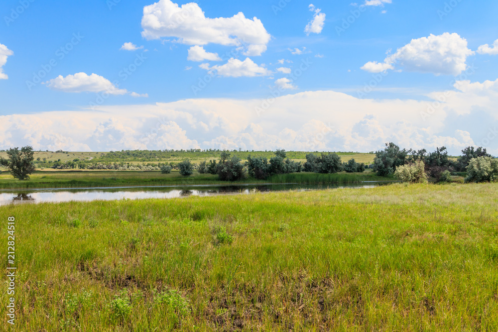 Summer landscape with small river and blue cloudy sky