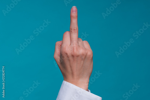 Schilderij op canvas close up female caucasian hand shows aggressive gesture with the middle finger on a blue pastel background