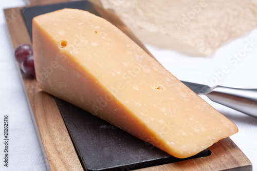 Piece of hard matured 3 years old dark yellow cheese close up