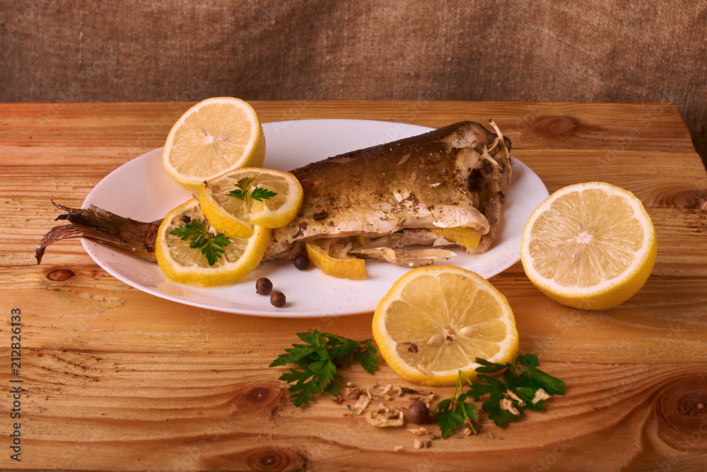 On a wooden table plate with roasted carp fish dorado with parsley, chives and lemon. Concept health food On a wooden table plate with roasted carp fish dorado with parsley, chives and lemon. Concept health food