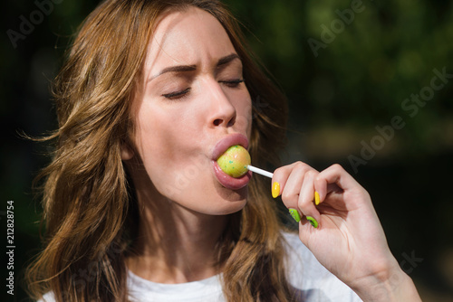 Beautiful girl sucks Lollipop in summer outdoors