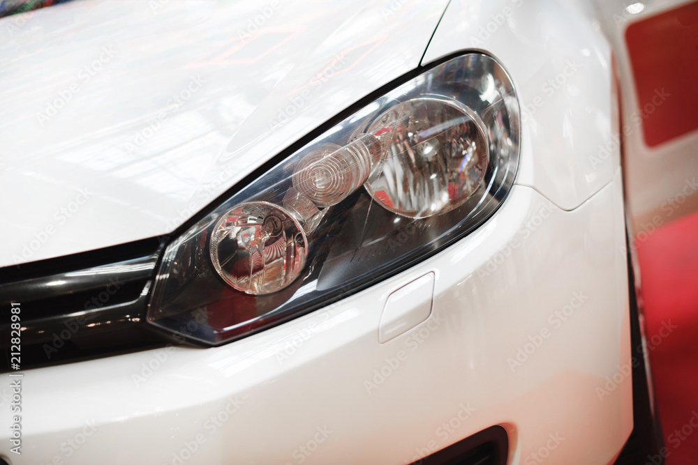 Left headlight of the new clean white sports car