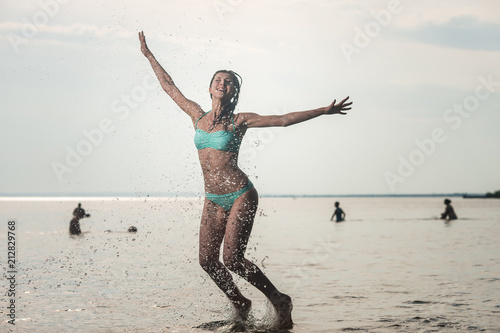 Young beautiful woman jumping in the sea, lots of splashing photo