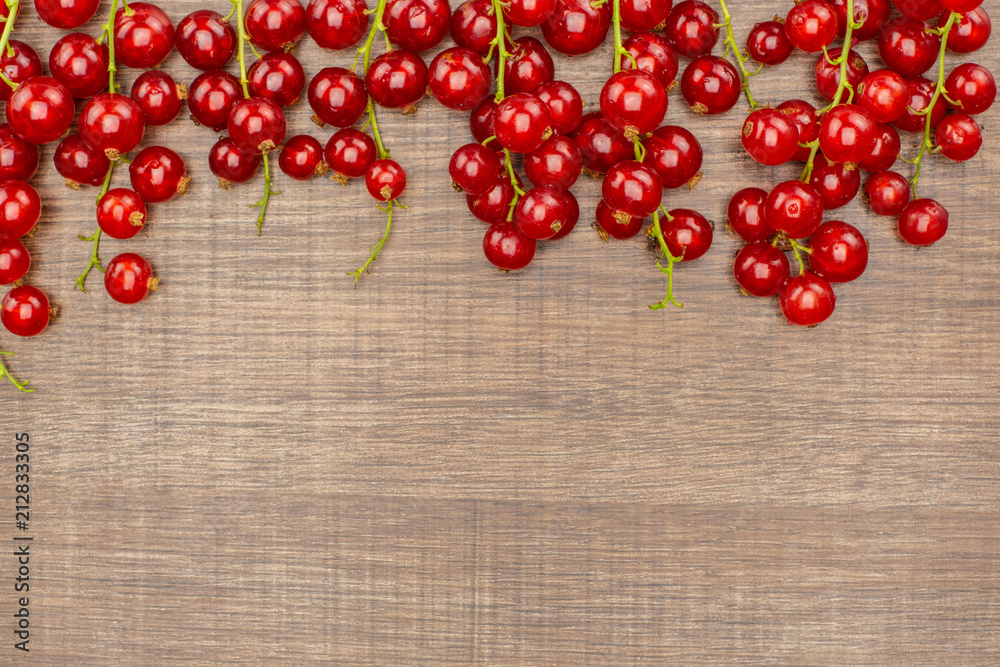 Red currant berry hanging flatlay isolated on brown wood.