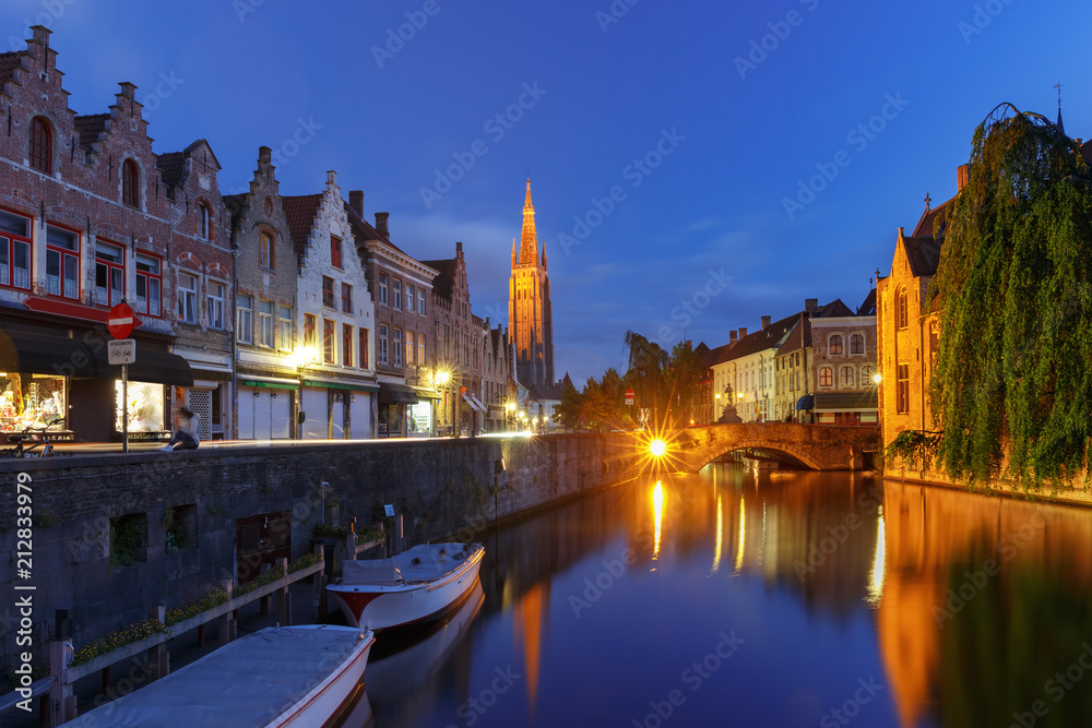 Scenic cityscape with a medieval fairytale canal and the quay Dijver and Church of Our Lady at night in Bruges, Belgium