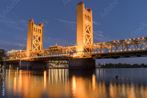 Tower Bridge and lights reflected on the Sacramento River. Sacramento and Yolo Counties, California, USA.