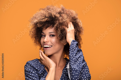 Happy african american lady smiling on yellow background.