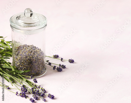 Fototapeta Naklejka Na Ścianę i Meble -  Glass jar with dried lavender and fresh lavender flowers on pink background