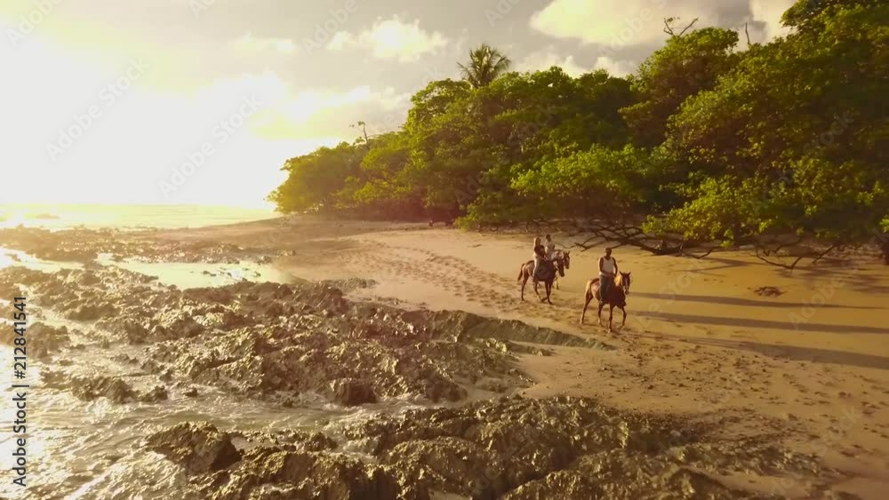 Drone footage of a sunset horseback ride on the beach, just next to the tropical jungle inSanta Teresa, Costa Rican