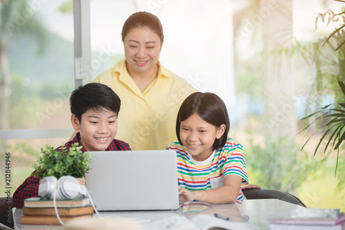 Asian teacher and kids entertaining using laptop computer.