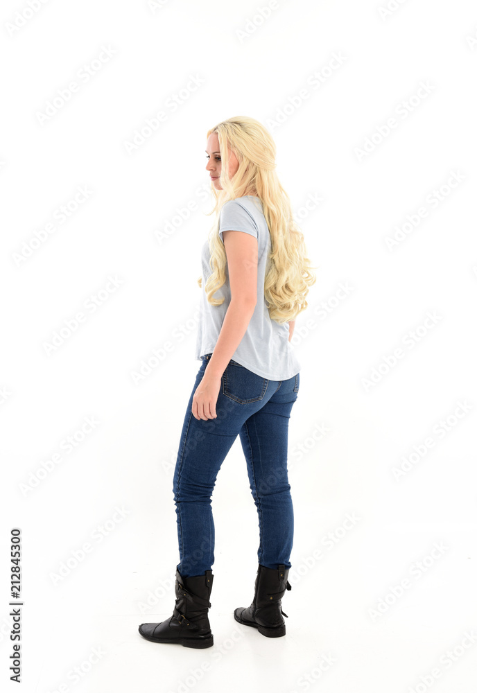 full length portrait of blonde girl wearing casual blue shirt and jeans, standing pose with back to the camera. isolated on white studio background. full length portrait of blonde girl wearing casual blue shirt and jeans, standing pose with back to the camera. isolated on white studio background.