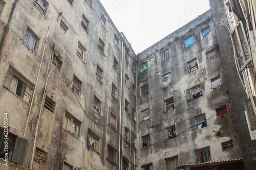 An abandoned building now occupied by social housing movement with white sky on the background. Internal view of the complex in C shape of this timeworn construction. San Paolo, Brazil, South America.