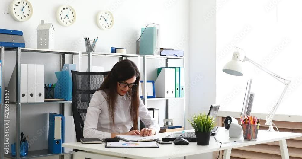 businesswoman taking off glasses and stretching, filling documents in modern office. businesswoman taking off glasses and stretching, filling documents in modern office.