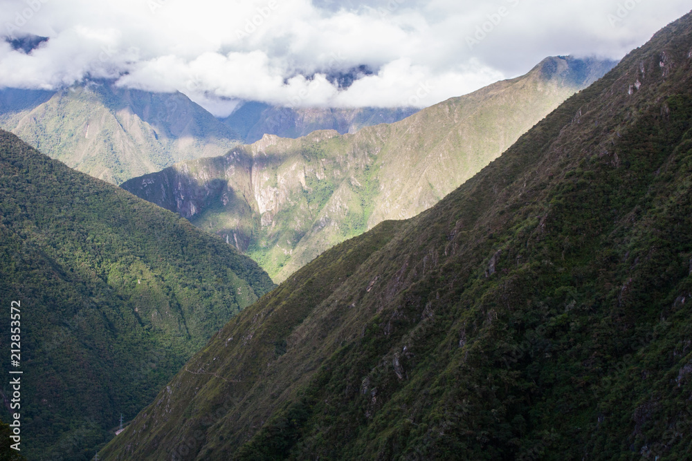 Naklejka premium Sun illuminating the valley while the clouds hide the mountain on the background. No people.