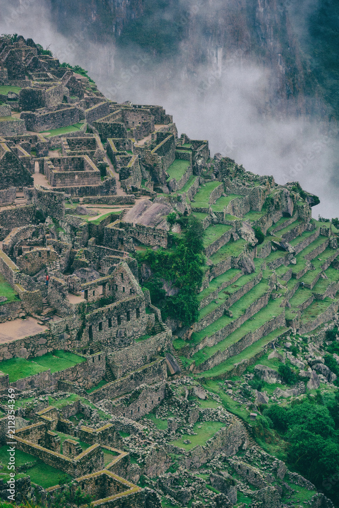 Obraz premium The secret and mysterious ruins of Machu Picchu covered in mist with the high Andes mountains on the background. The amazing prize of hiking the Inca Trail in Peru, South America.