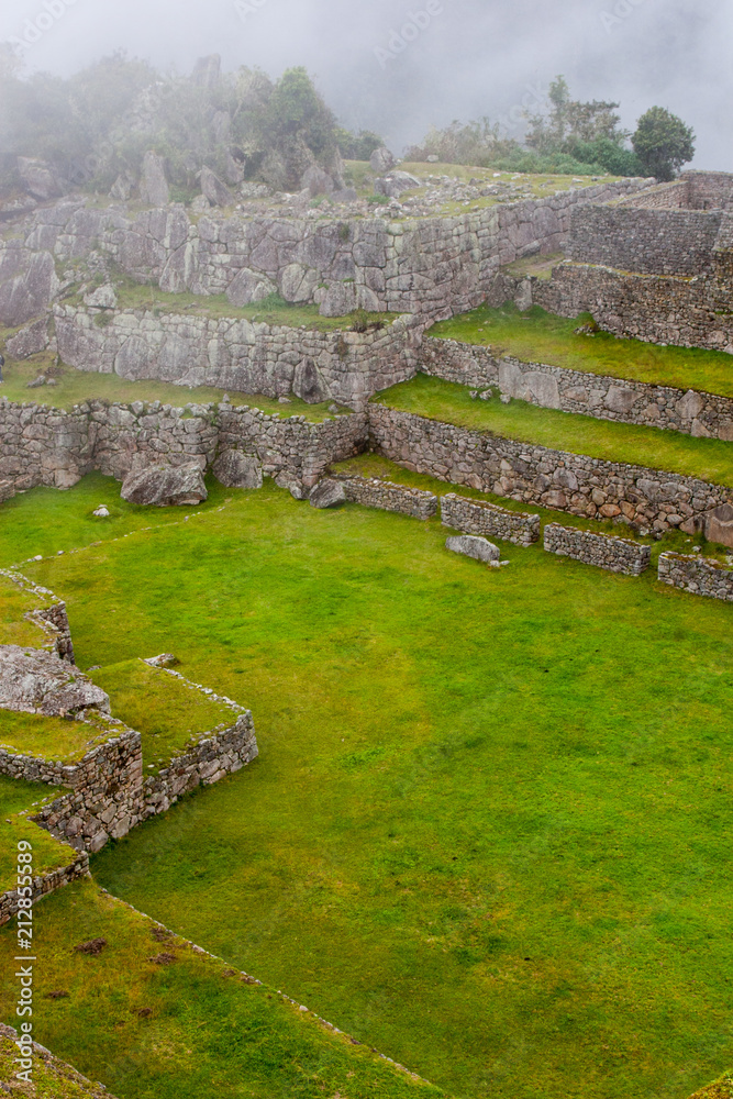 Vertical view of Machu Picchu stone ruins lost in the wild nature of the Andes mountains. Peru. South America. No people.