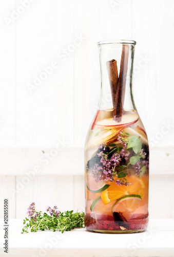 Summer fruit lemonade in a glass bottle on a light wooden table