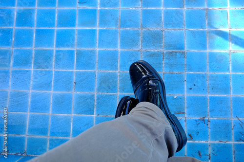 man black leather shoe with brown jeans lower and milling around legs into a dry pool