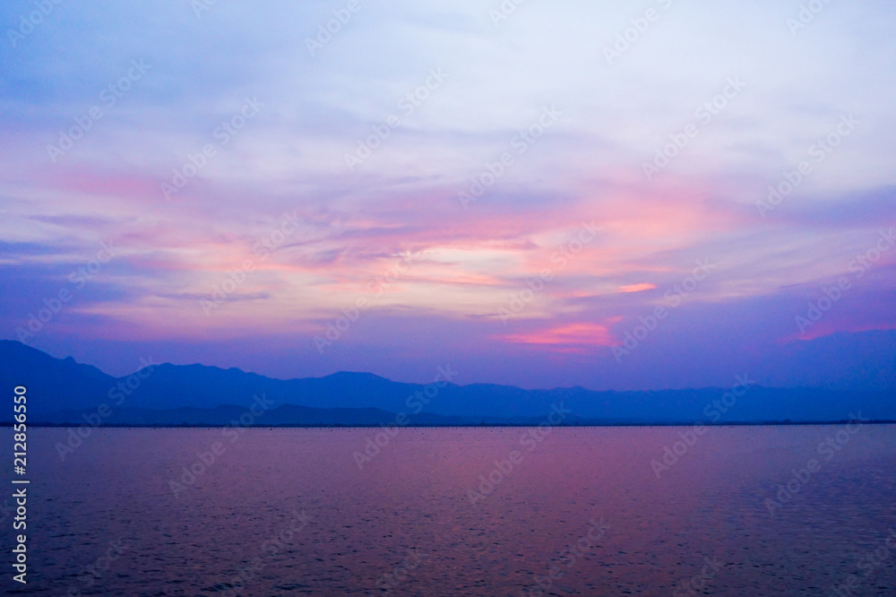 Fototapeta premium landscape of clouds sky sunset over lake with mountains