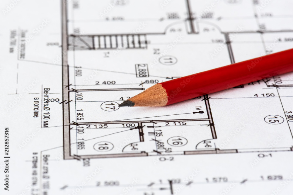 The architectural plan of the house is printed on a white sheet of paper. A red pencil on it. June 2018, Russia, Moscow The architectural plan of the house is printed on a white sheet of paper. A red pencil on it. June 2018, Russia, Moscow