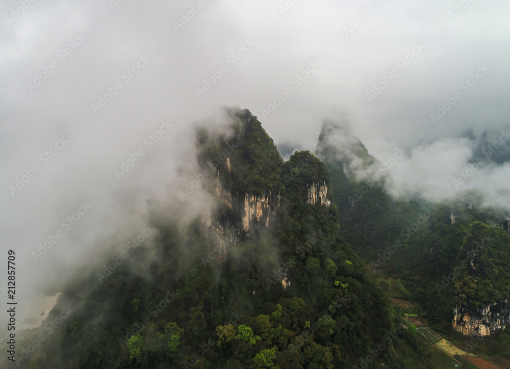 aerial view of cloudscape above farmland and mountain