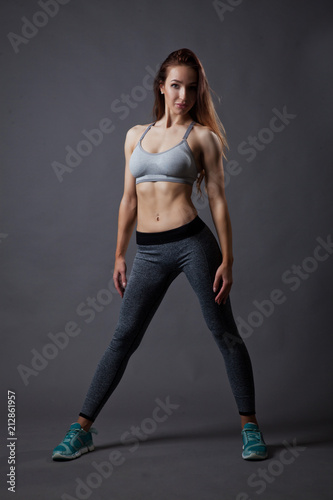 Sporty and sexy slim girl posing on grey background