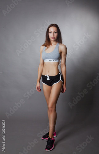 Sporty and sexy slim girl posing on grey background © Dancer01