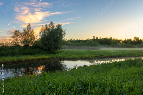 Summer countryside, a small river and fog over the field