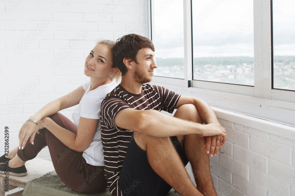 Obraz premium Happy girl and guy, cute couple looking out the window in their new home