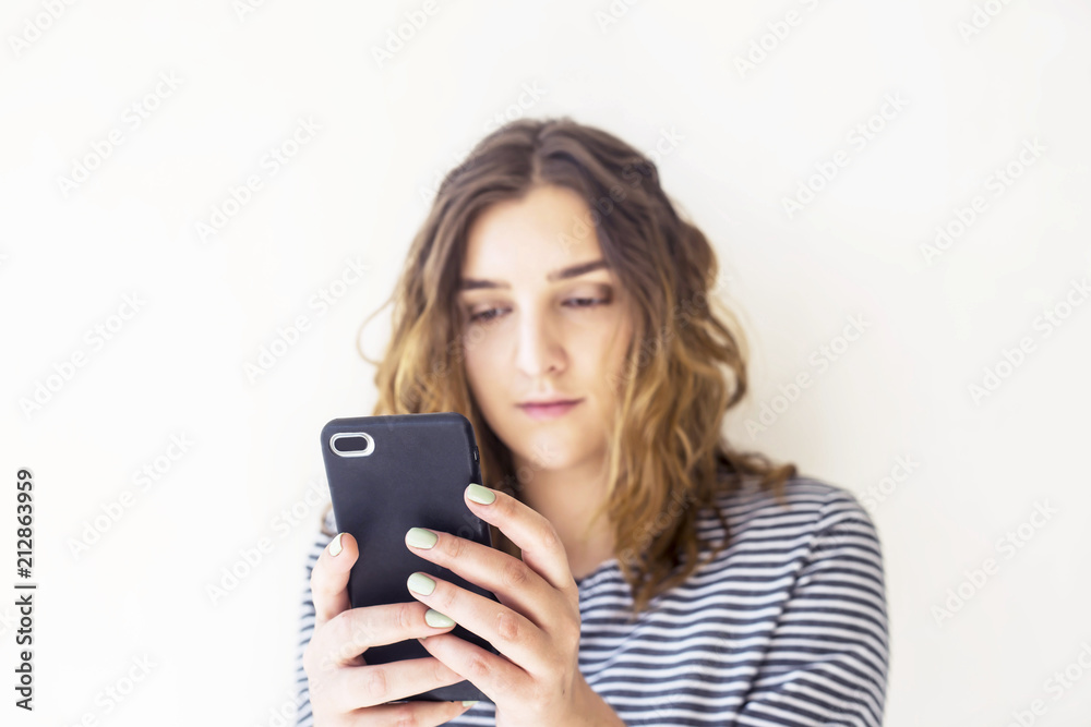 A girl is holding a smartphone and looking at the screen. Technology and online life A girl is holding a smartphone and looking at the screen. Technology and online life